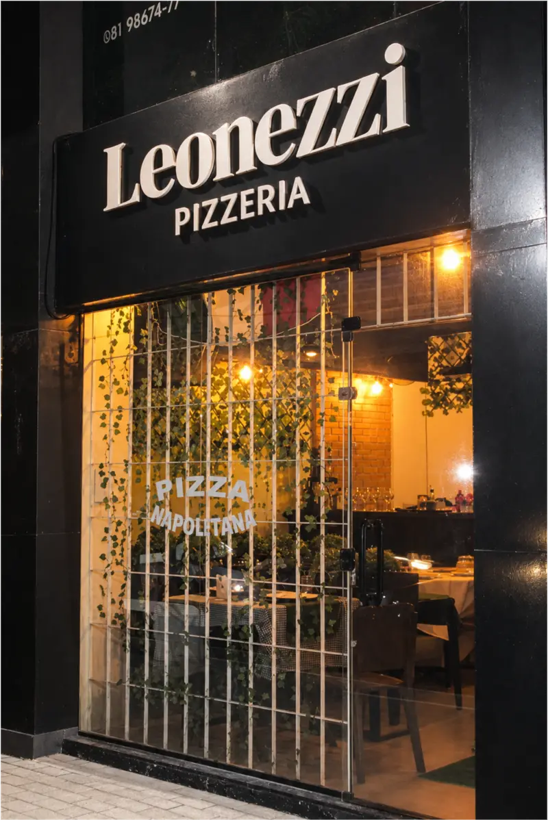 Leonezzi Pizzeria storefront at night, the lit dining room seen from the street